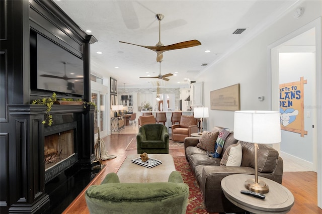 living room featuring ceiling fan, ornamental molding, and wood-type flooring