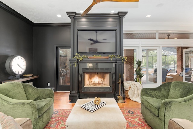 sitting room featuring ceiling fan, ornamental molding, and wood-type flooring