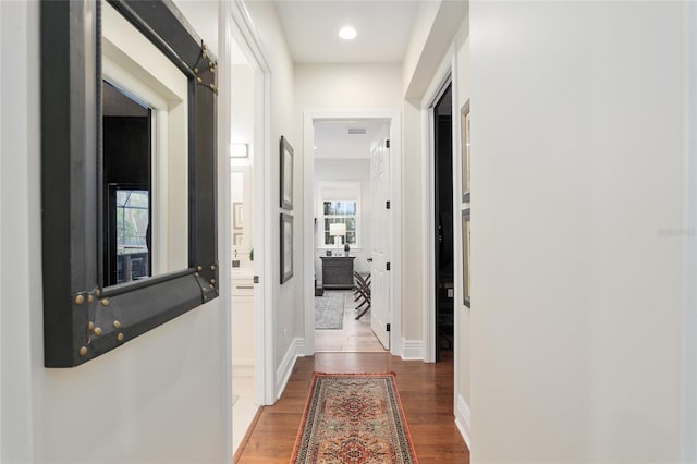 hall featuring a healthy amount of sunlight and dark wood-type flooring