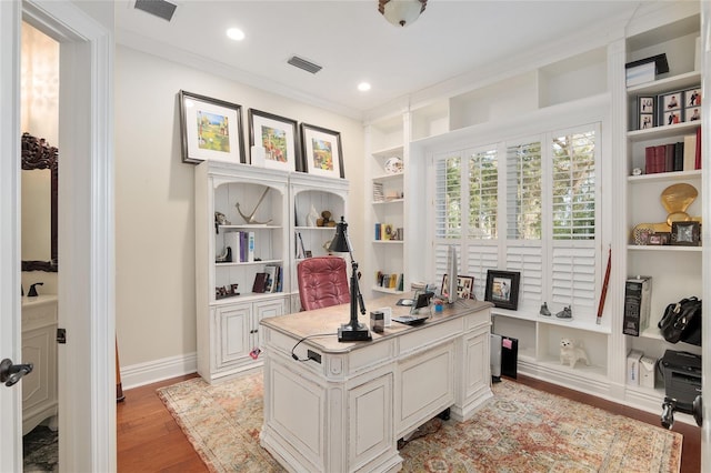 office with crown molding, built in shelves, and light hardwood / wood-style floors