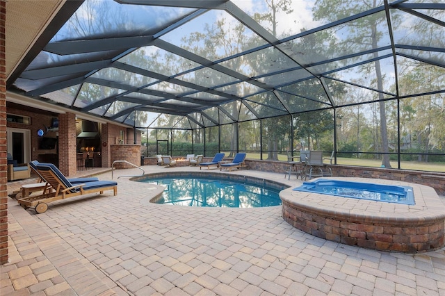 view of pool with an outdoor fireplace, an in ground hot tub, glass enclosure, and a patio area