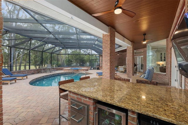 view of swimming pool with area for grilling, ceiling fan, a patio area, a bar, and an in ground hot tub