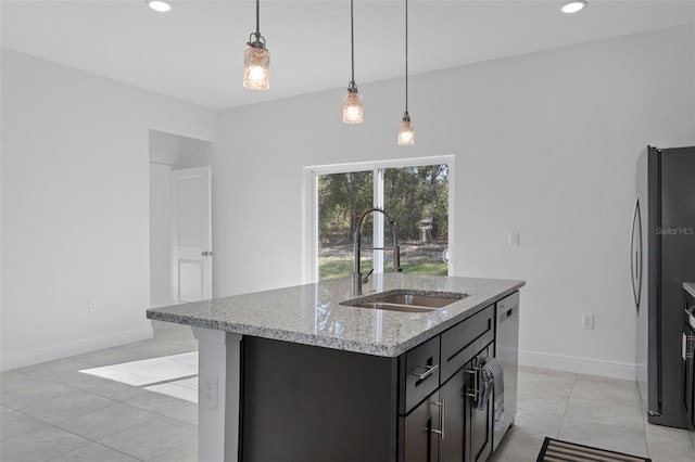 kitchen featuring light stone countertops, decorative light fixtures, a center island with sink, appliances with stainless steel finishes, and sink