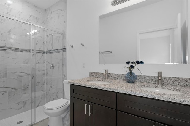 bathroom featuring a shower with door, vanity, and toilet