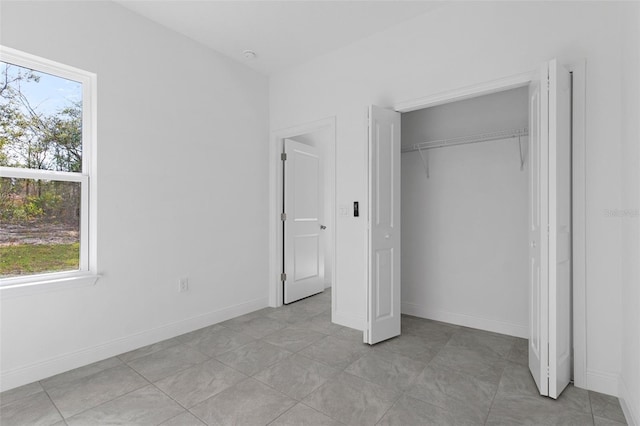 unfurnished bedroom with a closet, multiple windows, and light tile patterned floors