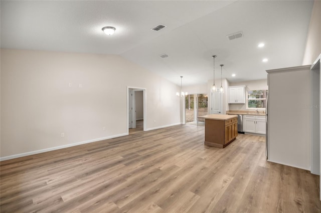 kitchen with white cabinets, a center island, an inviting chandelier, lofted ceiling, and pendant lighting