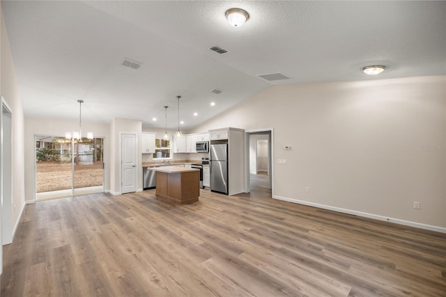 kitchen with light hardwood / wood-style flooring, a center island, decorative light fixtures, white cabinets, and appliances with stainless steel finishes