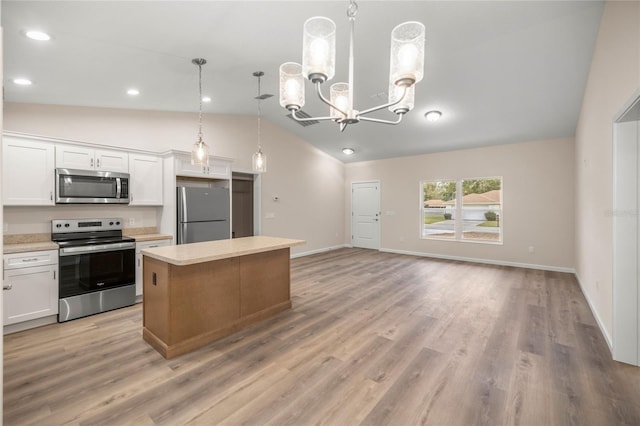 kitchen with appliances with stainless steel finishes, hanging light fixtures, a center island, white cabinetry, and lofted ceiling