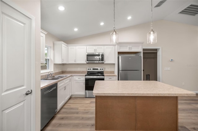 kitchen featuring sink, decorative light fixtures, white cabinets, vaulted ceiling, and appliances with stainless steel finishes