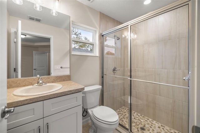 bathroom with toilet, an enclosed shower, and vanity