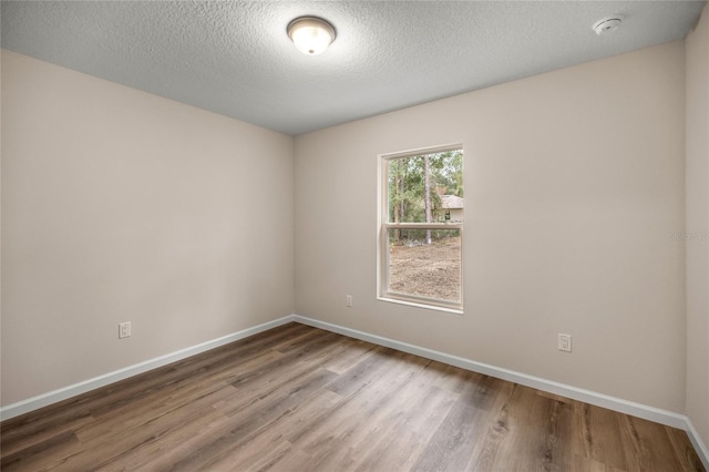 spare room featuring a textured ceiling and hardwood / wood-style flooring