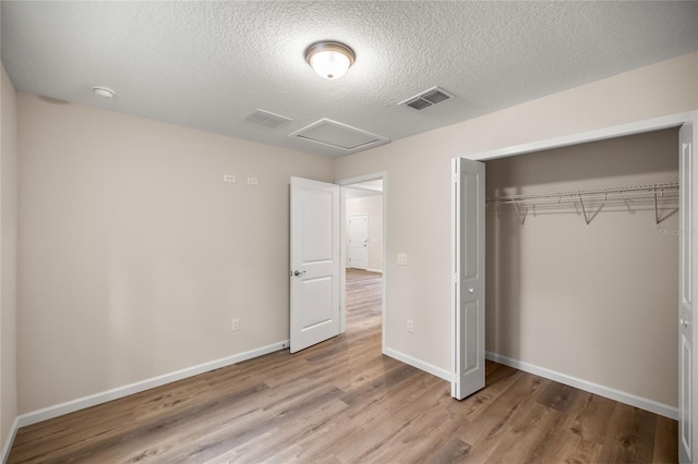 unfurnished bedroom featuring a textured ceiling, a closet, and light hardwood / wood-style flooring