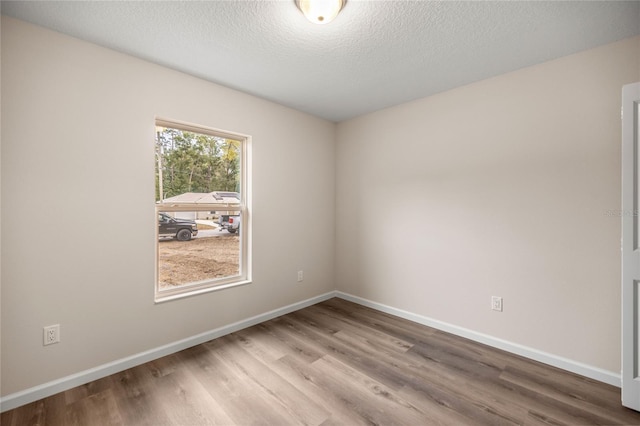 spare room with a textured ceiling and hardwood / wood-style floors