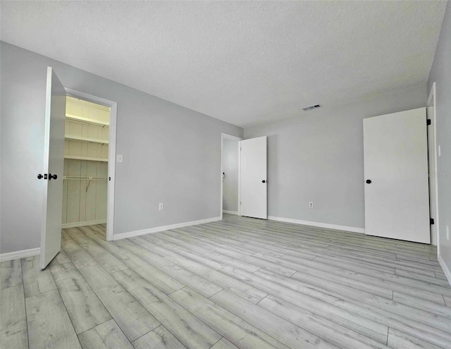 empty room with light hardwood / wood-style floors and a textured ceiling