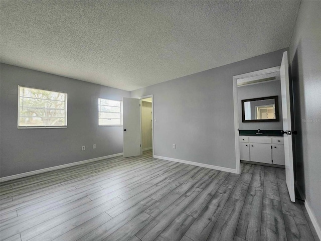 empty room featuring a textured ceiling, light hardwood / wood-style flooring, and sink