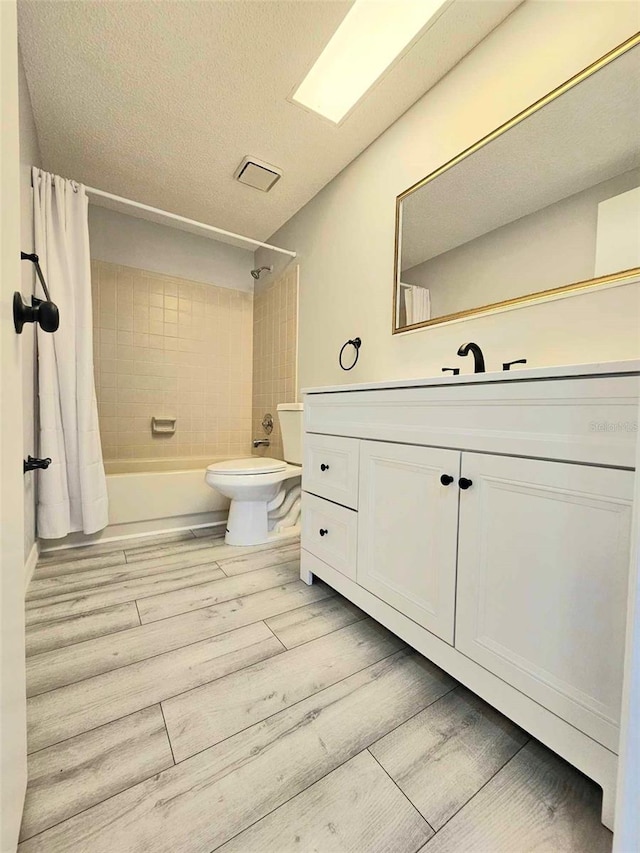 full bathroom with toilet, hardwood / wood-style flooring, a textured ceiling, shower / bath combo, and vanity