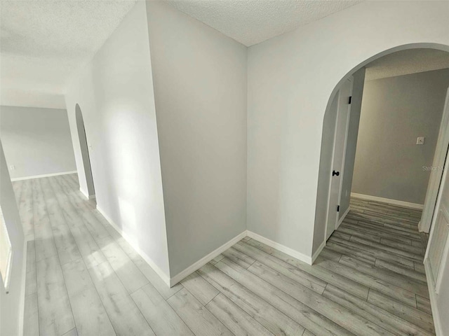 hall featuring a textured ceiling and light hardwood / wood-style flooring