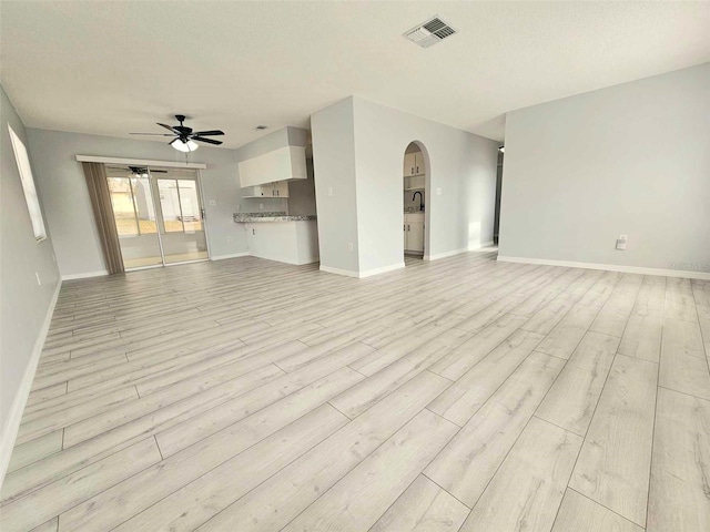 unfurnished living room featuring ceiling fan, light hardwood / wood-style flooring, and a textured ceiling