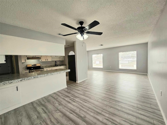 kitchen with sink, light stone counters, ceiling fan, light hardwood / wood-style flooring, and stainless steel range with electric stovetop