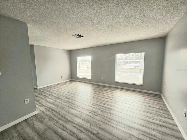 empty room with a textured ceiling and light wood-type flooring