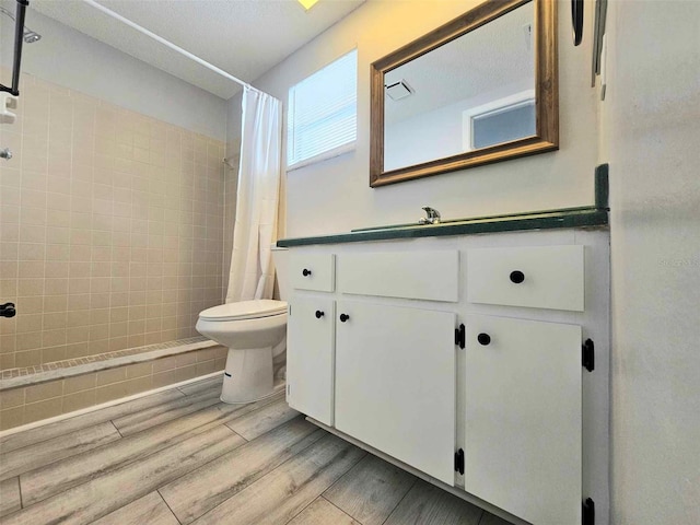 bathroom with toilet, vanity, hardwood / wood-style flooring, and curtained shower