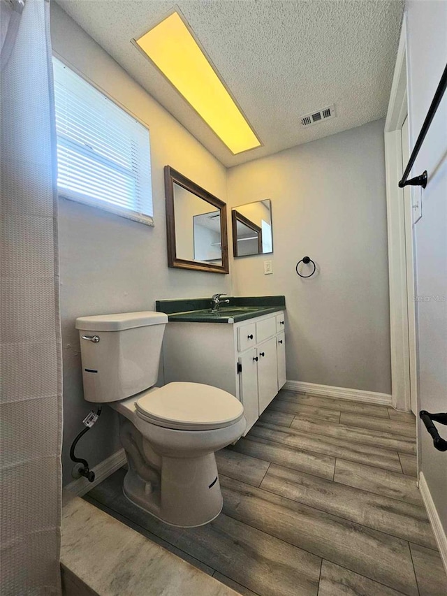 bathroom with toilet, vanity, and hardwood / wood-style flooring