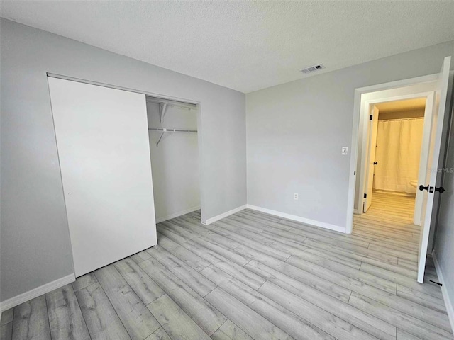 unfurnished bedroom with light hardwood / wood-style floors, a closet, and a textured ceiling