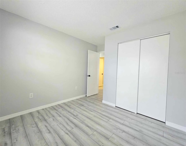 unfurnished bedroom with a closet and light wood-type flooring