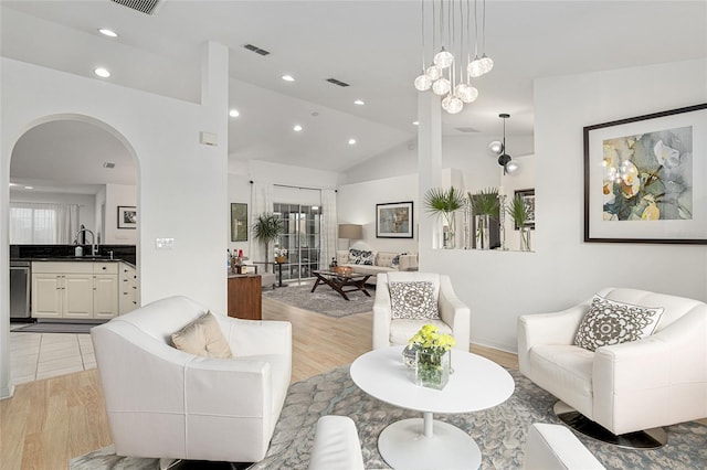 living room with sink, vaulted ceiling, and light hardwood / wood-style flooring