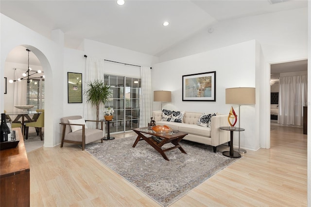 living room featuring high vaulted ceiling, light wood-type flooring, and a notable chandelier