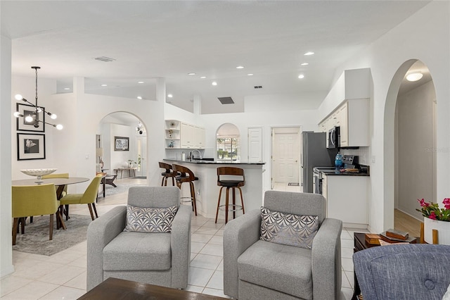 tiled living room with sink, an inviting chandelier, and lofted ceiling