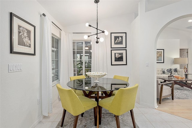 dining room featuring an inviting chandelier, vaulted ceiling, and light tile patterned floors