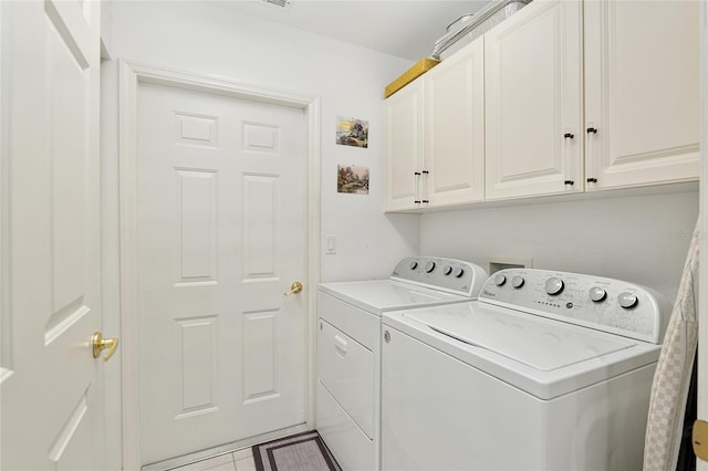 laundry room with washer and dryer, cabinets, and light tile patterned floors