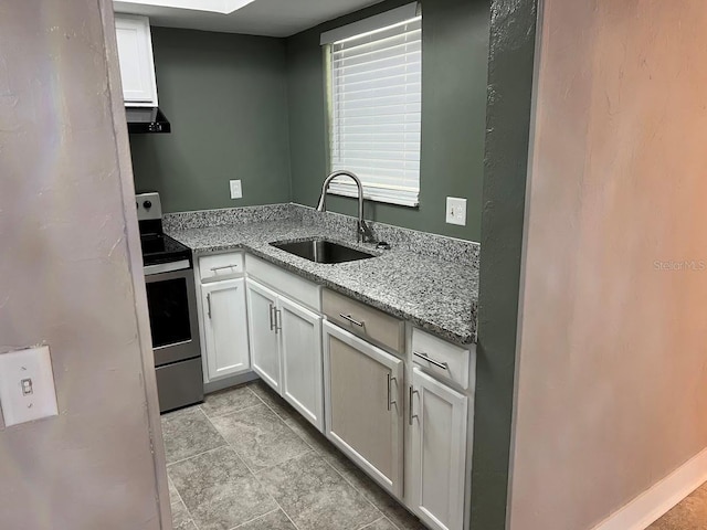 kitchen with sink, white cabinetry, electric range, and light stone counters