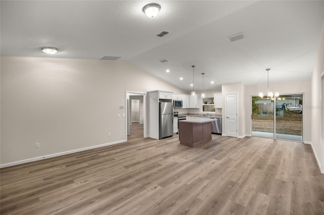 kitchen with decorative light fixtures, white cabinetry, vaulted ceiling, a kitchen island, and appliances with stainless steel finishes