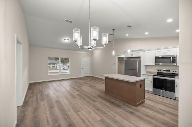 kitchen with stainless steel appliances, a kitchen island, white cabinets, decorative light fixtures, and lofted ceiling