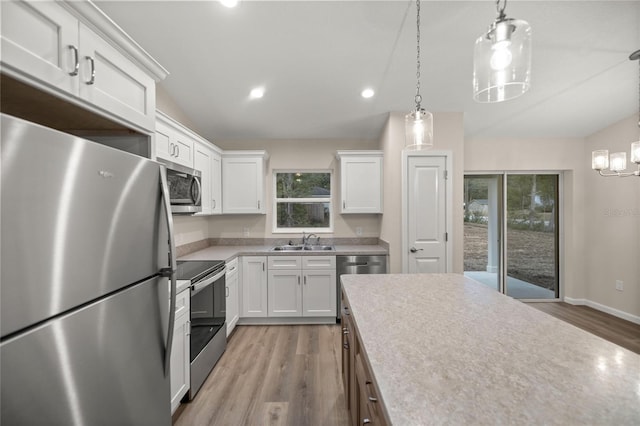 kitchen with stainless steel appliances, sink, white cabinets, wood-type flooring, and pendant lighting