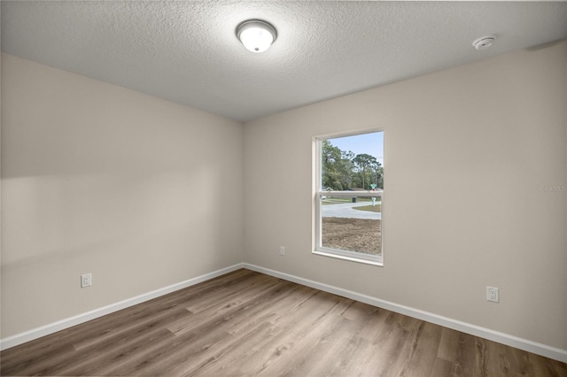 spare room featuring wood-type flooring and a textured ceiling