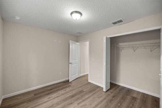 unfurnished bedroom with a textured ceiling, a closet, and wood-type flooring