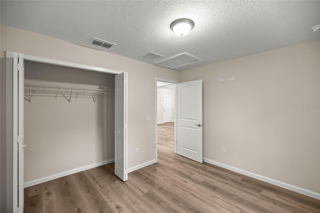 unfurnished bedroom featuring a textured ceiling, light wood-type flooring, and a closet