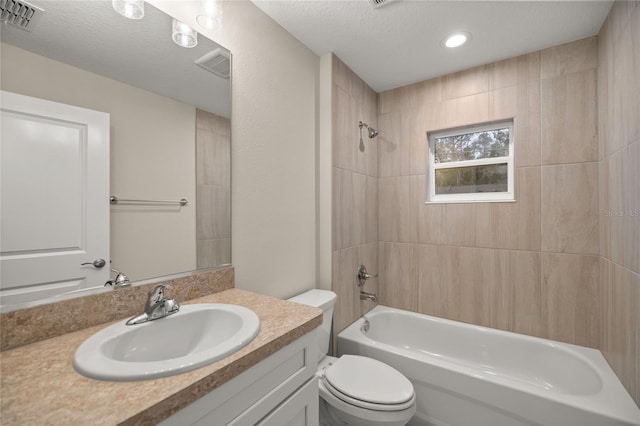 full bathroom with toilet, vanity, a textured ceiling, and tiled shower / bath combo