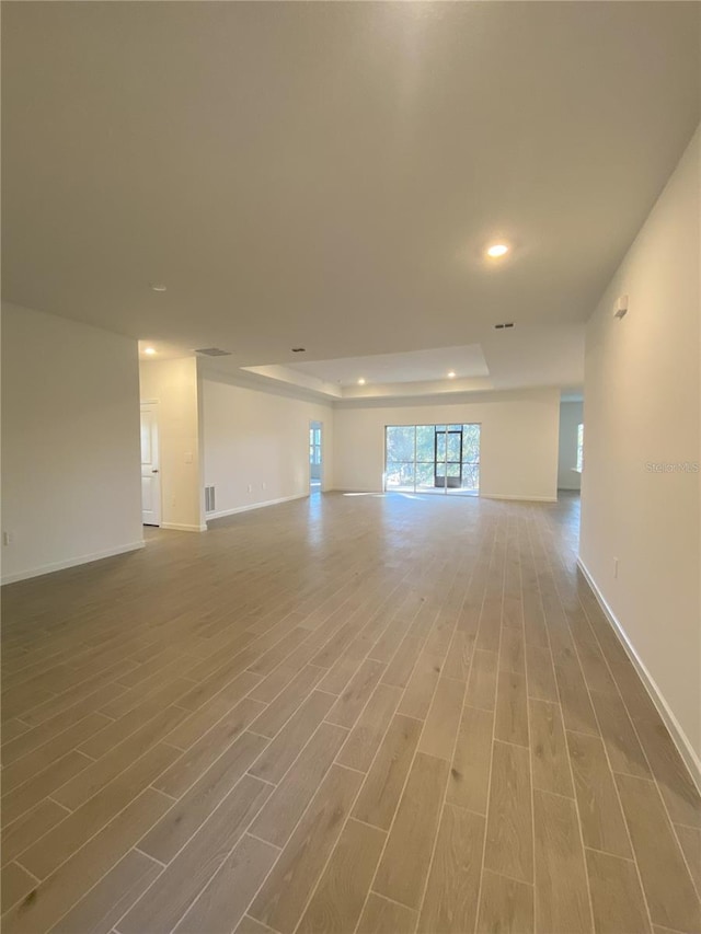 unfurnished room with hardwood / wood-style flooring and a raised ceiling