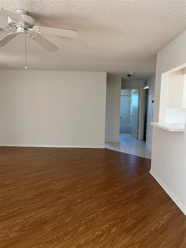 unfurnished room with light wood-type flooring, ceiling fan, and a textured ceiling