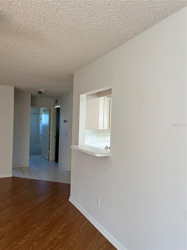 hall with a textured ceiling and light hardwood / wood-style flooring