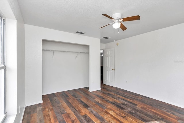 unfurnished bedroom with a closet, ceiling fan, a textured ceiling, and dark hardwood / wood-style flooring