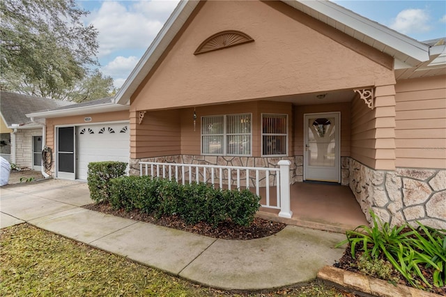 view of exterior entry with a garage and a porch