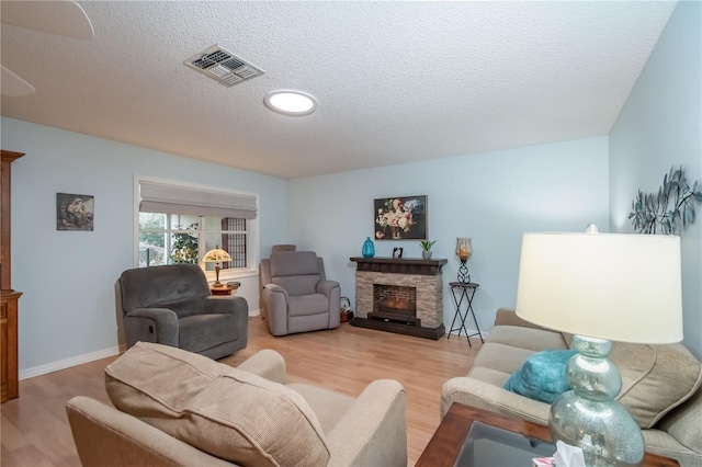 living room featuring a fireplace, light wood-type flooring, and a textured ceiling