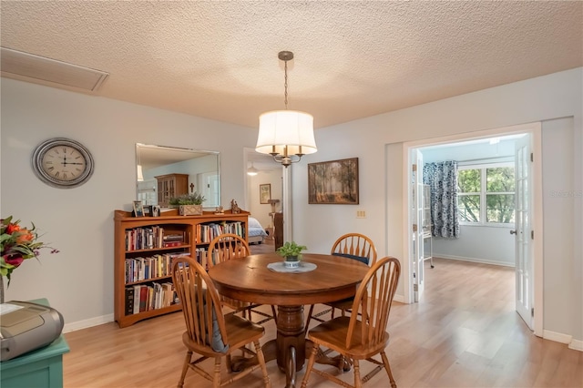 dining space featuring a textured ceiling and light hardwood / wood-style flooring