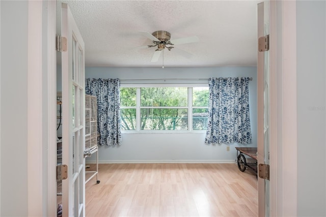 unfurnished room with ceiling fan, light hardwood / wood-style flooring, and a textured ceiling