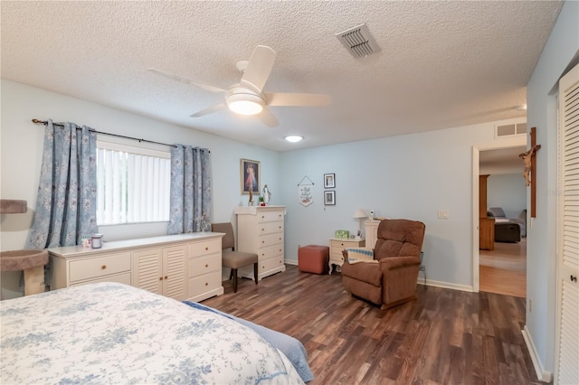 bedroom with dark wood-type flooring, a textured ceiling, a closet, and ceiling fan